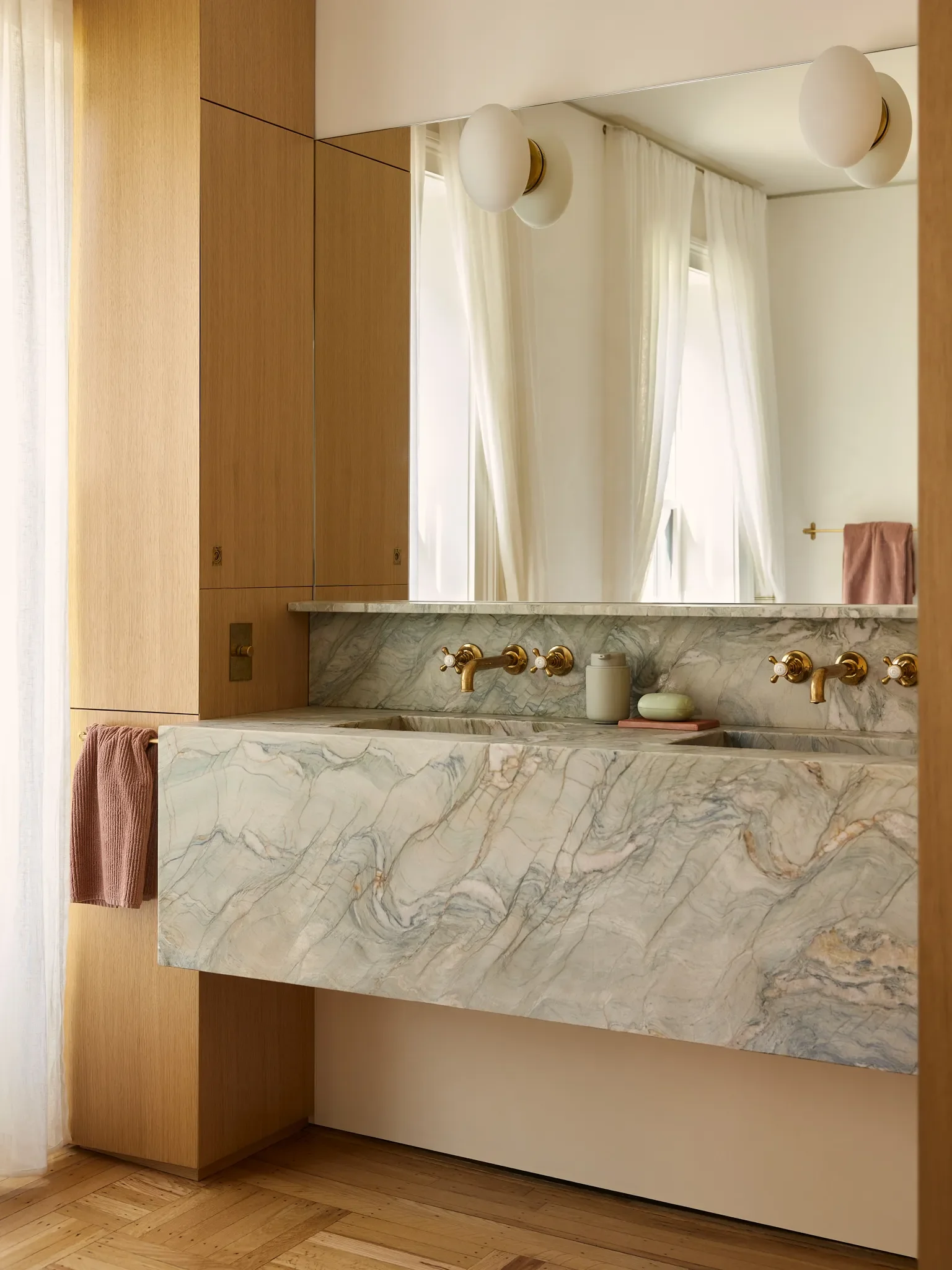 A custom marble sink is the showstopper of this space, which also includes a tub and fixtures by Waterworks and refinished parquet floors.
